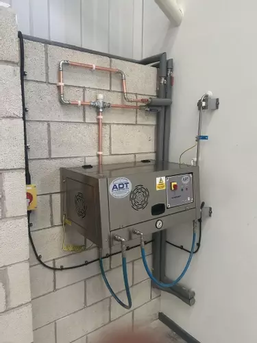 Electric wall-mounted three-phase pressure washer installed with copper inlet pipework at a manufacturing facility in Nottingham.